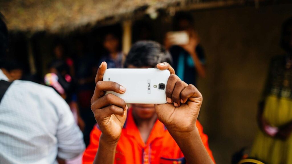 Internet in het buitenland: roaming, eSIM en handige tips 4 Jongen met telefoon en oranje shirt maakt foto van camera