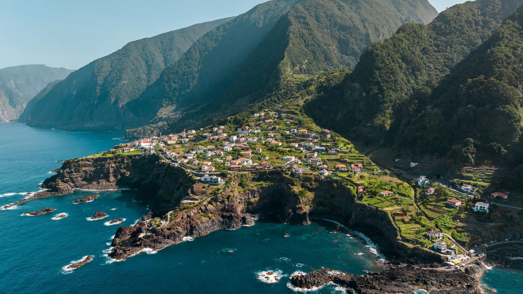Scenic aerial view of a coastal village in Madeira, Portugal with lush green landscapes and rocky shores