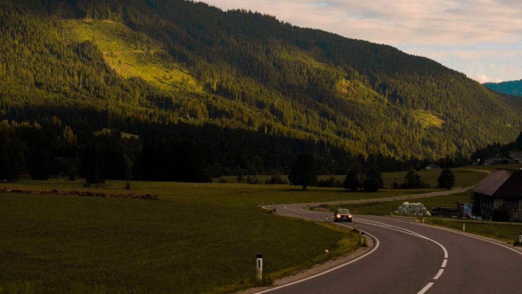 Kronkelende weg in Oostenrijk onder een dramatische avondlucht en omringd door weelderige groene bergen